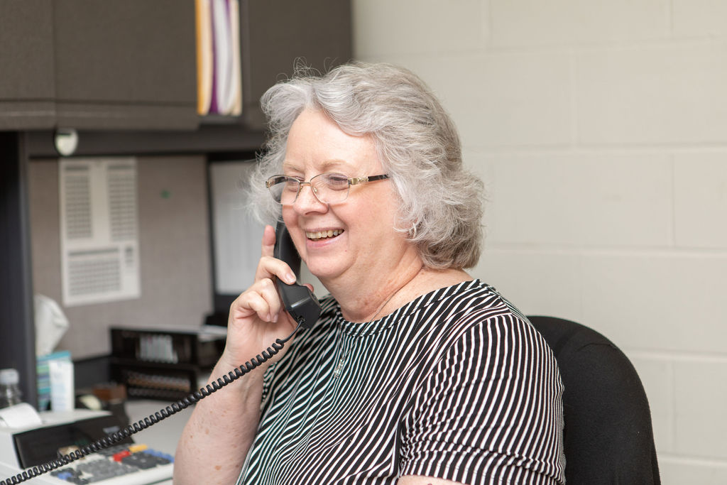 Hutchens Rentz-Eden employee answering the phone at a desk, smiling.