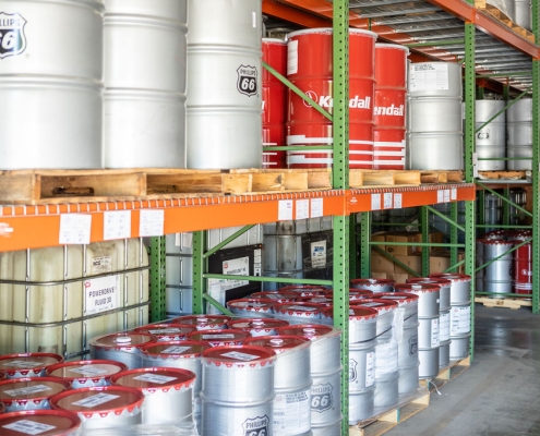 50 gallon metal drums of lubricant products on a metal shelf