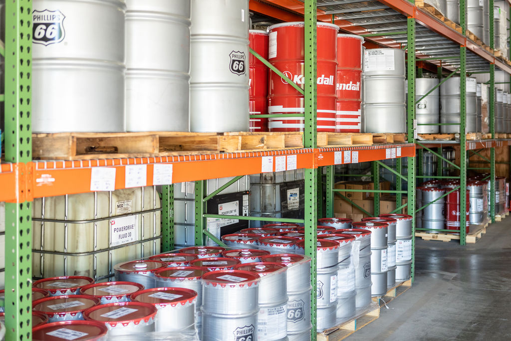 50 gallon metal drums of lubricant products on a metal shelf