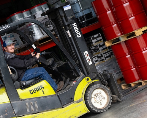 Hutchens forklift operator moving a pallet of red barrels