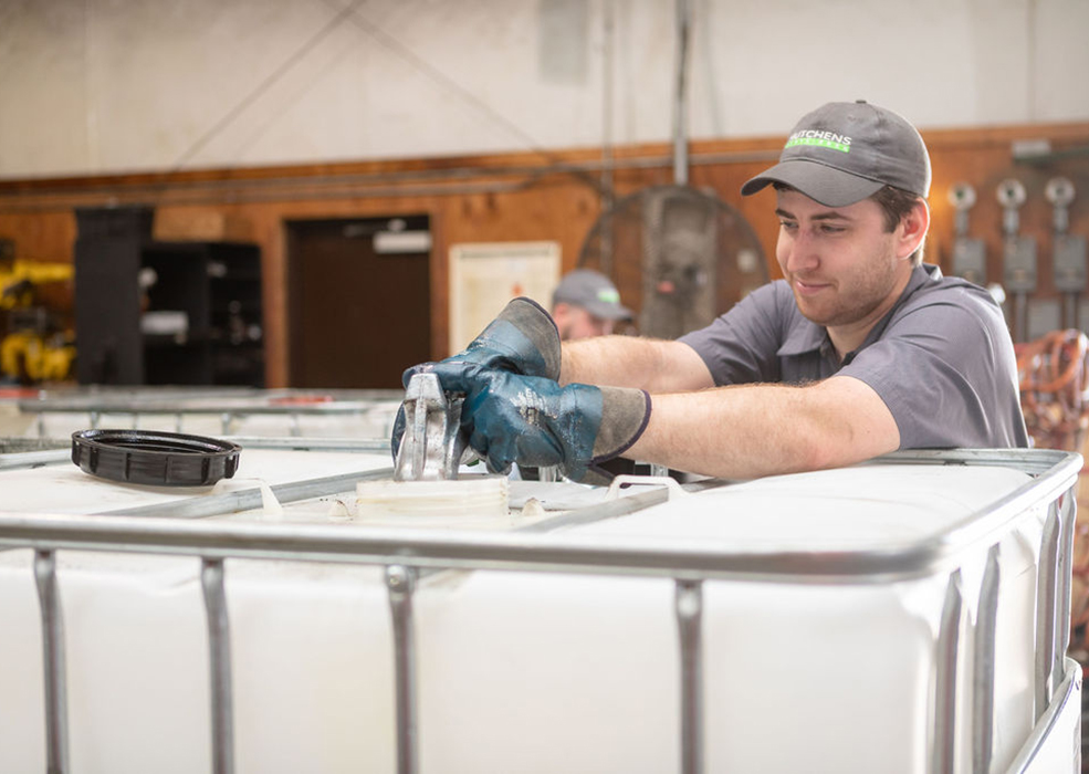 Hutchens technician filling a large tote with lubricant