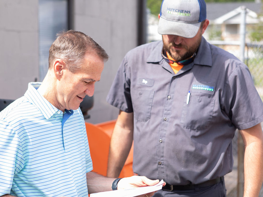 Tim Hutchens and associate looking at a sheet of paper and smiling